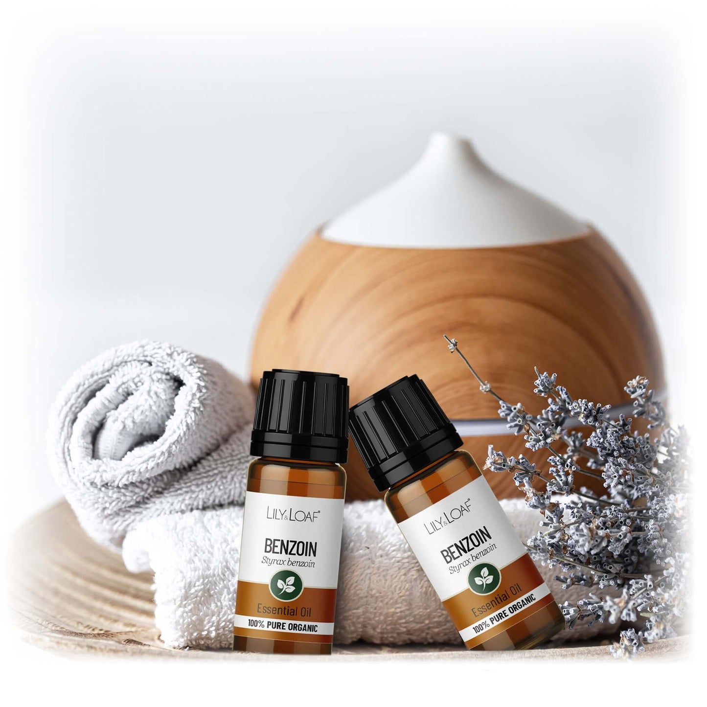 Two bottles of Lily & Loaf Benzoin oil with a wooden diffuser and decorative elements on a light background.
