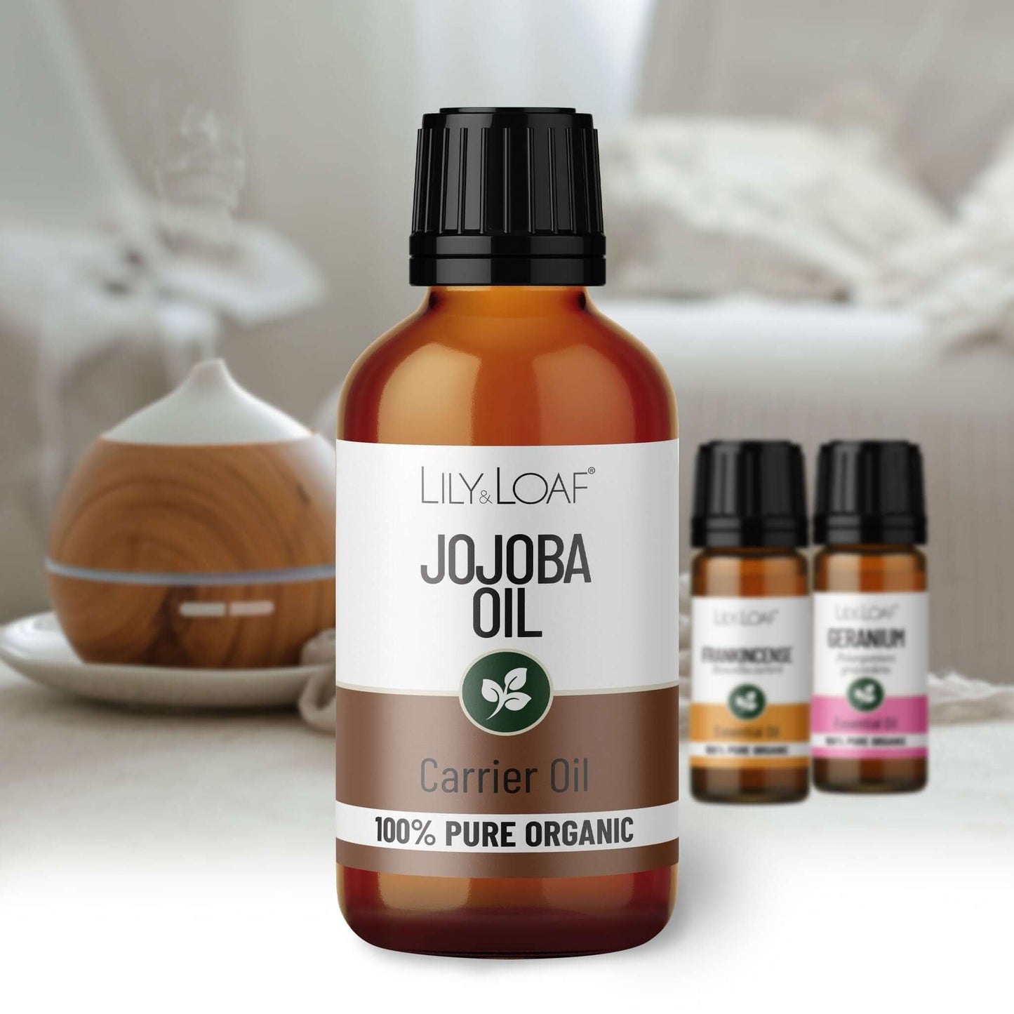 Bottle of Lily & Loaf Jojoba Oil with other essential oil bottles in the background.