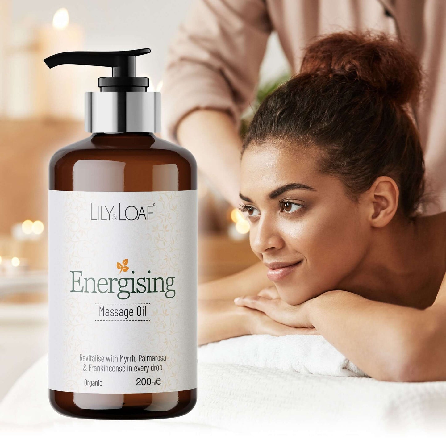 Bottle of Lily & Loaf Energising Massage Oil with a woman receiving a massage in the background