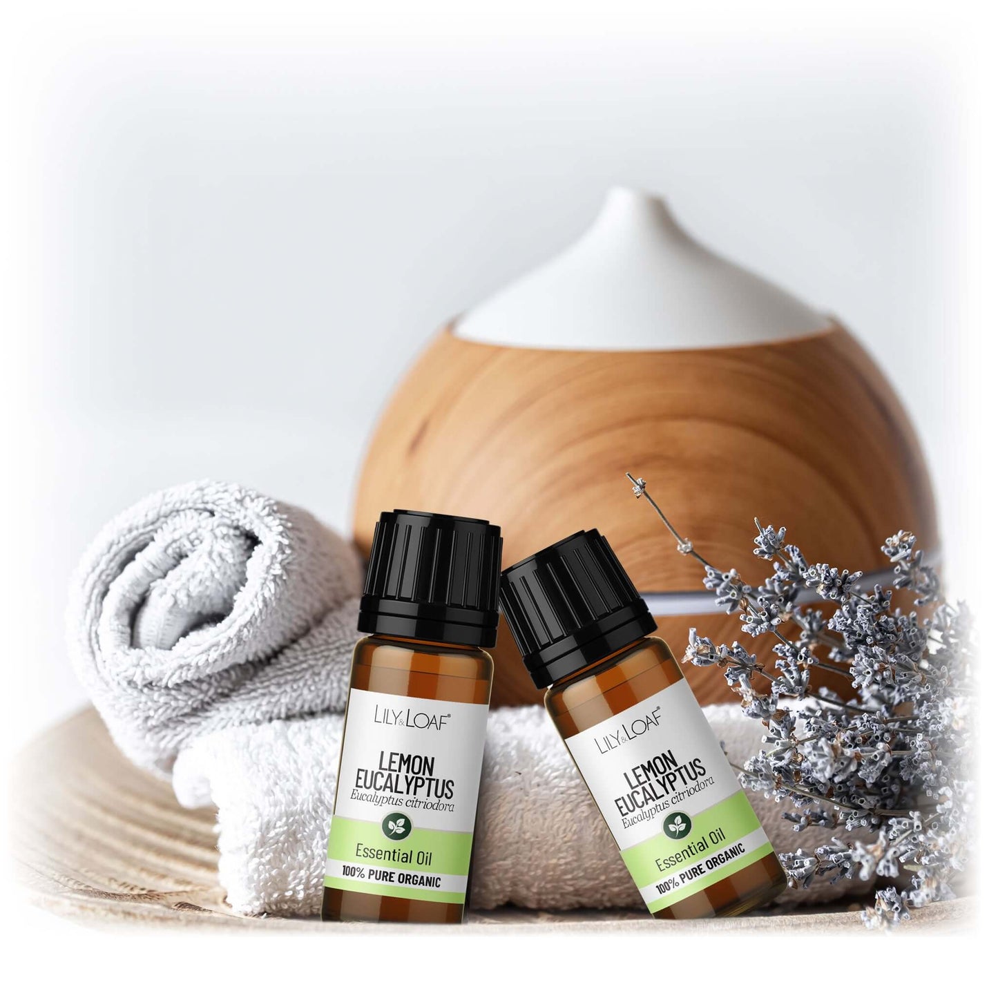 Two bottles of Lemon Eucalyptus essential oil with a diffuser and towel on a light background