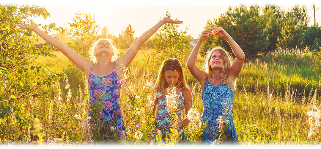 Three girls in a meadow playing with flowers