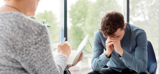 A man at a doctors appointment with his head in his hands crying