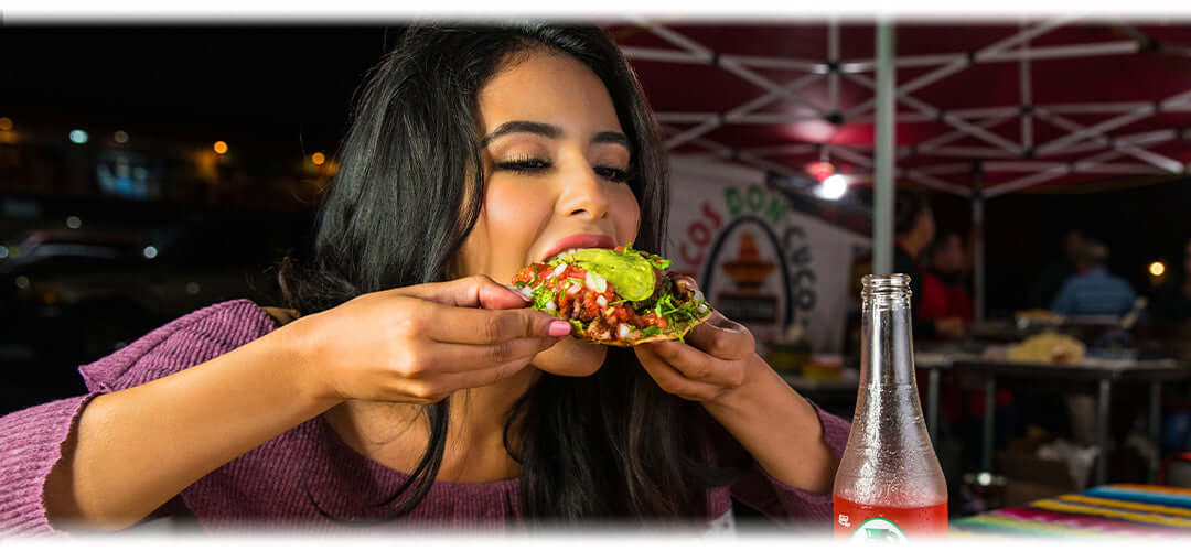 A woman enjoying a delicious stuffed taco