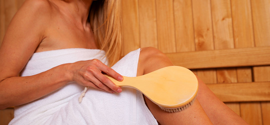 Lady dry brushing her legs in a sauna