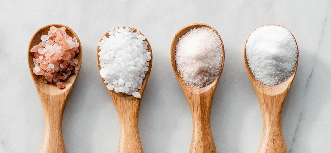 wooden spoons filled with different types of salt