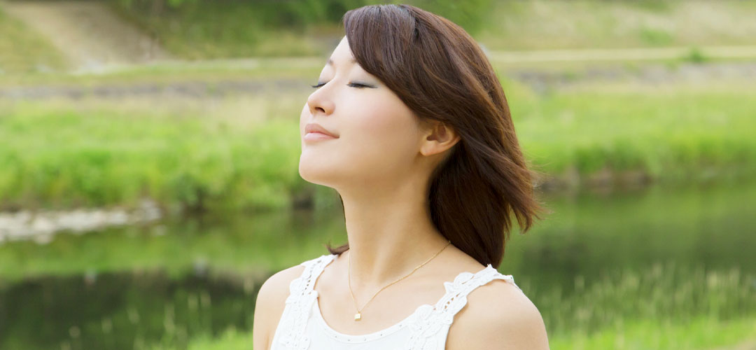 Calm woman breathing deeply in nature, symbolising the importance of a healthy circulatory system for overall well-being and oxygen flow
