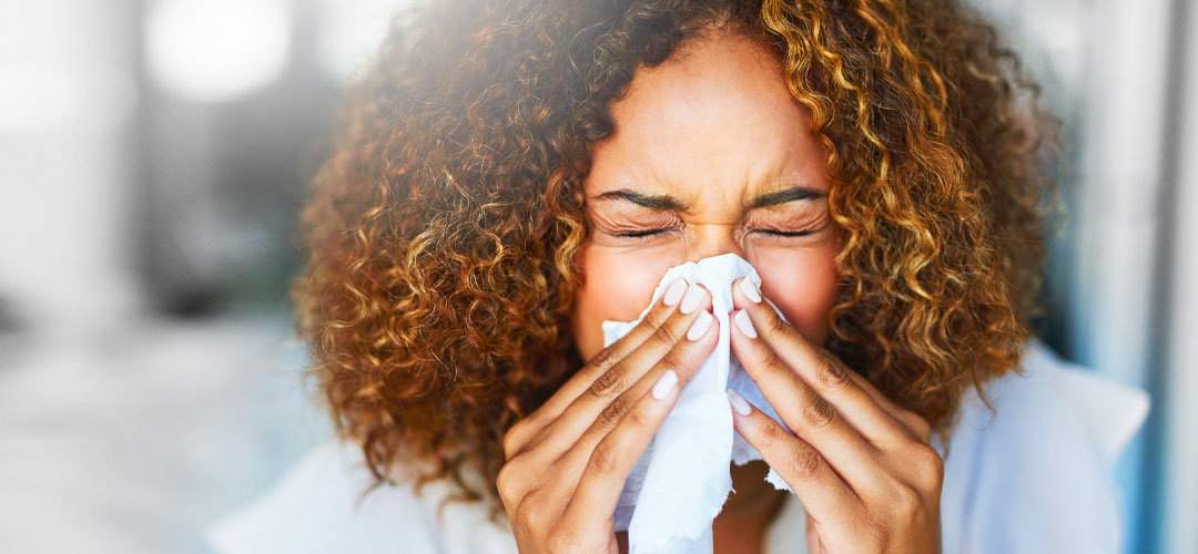 Female sneezing into a tissue