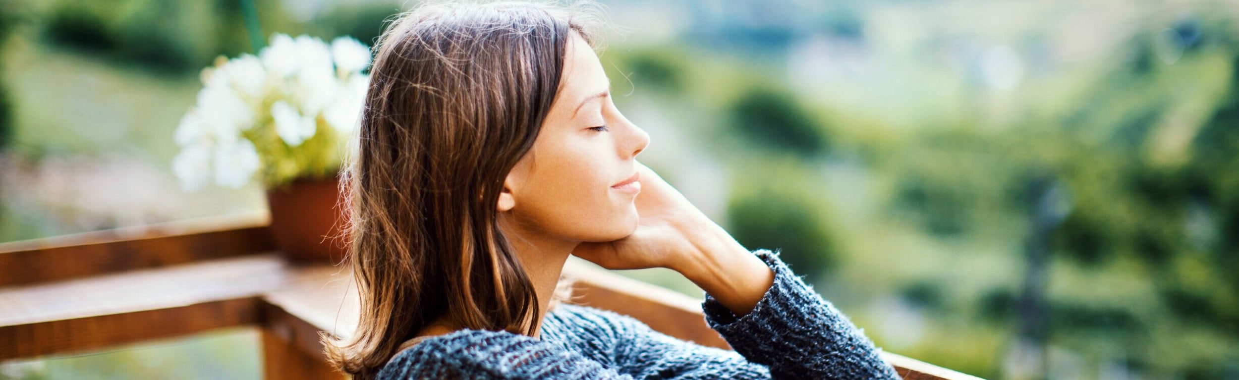 Relaxed woman enjoying nature with eyes closed, symbolising mindfulness, stress relief, and guidance from a hypnotherapist and life coach