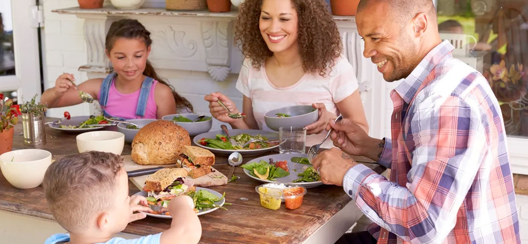 Happy family enjoying a healthy meal outdoors, illustrating how to easily incorporate a 10-day detox into a busy lifestyle through balanced eating