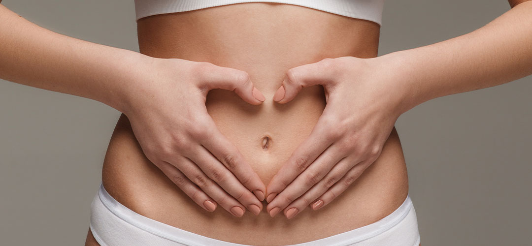 Close-up of hands forming a heart shape over the stomach, symbolising the importance of a healthy digestive system for overall well-being