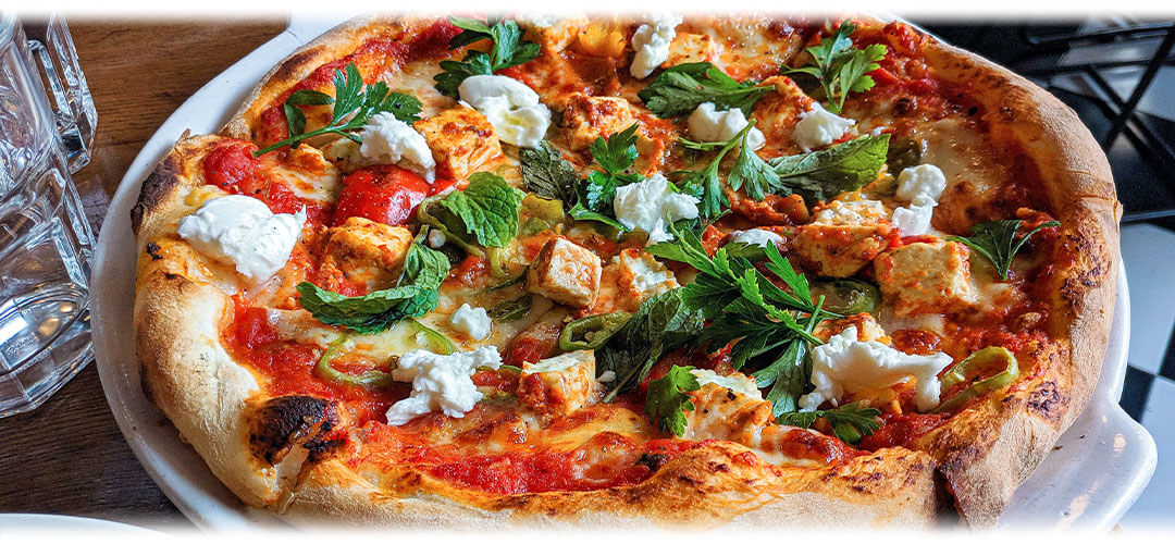 Freshly baked pizza topped with herbs, cheese, and vegetables, representing ways to manage stress-induced cravings