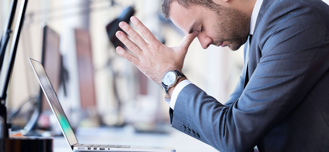 Male suffering headache at his office desk
