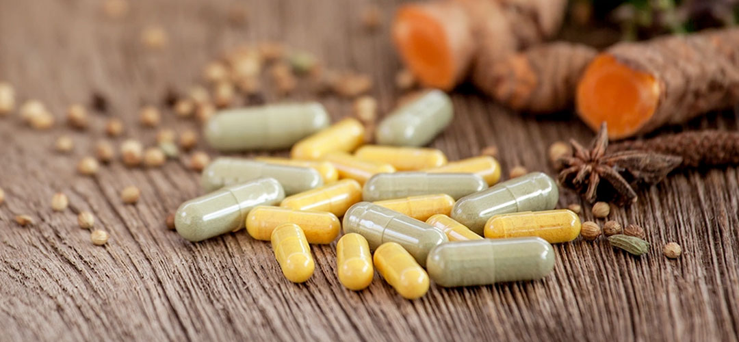 Herbal supplements and turmeric roots on a wooden surface, highlighting the role of herbs in supporting detoxification and body cleansing