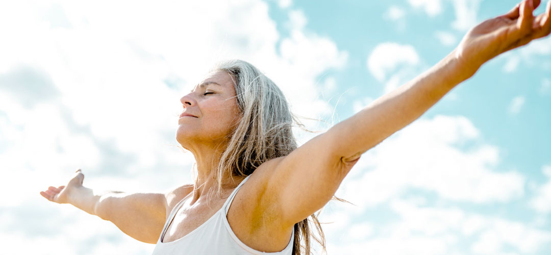 Relaxed woman with arms outstretched under a bright sky, symbolising rejuvenation, detox benefits, and the Healthy Starter Programme's support