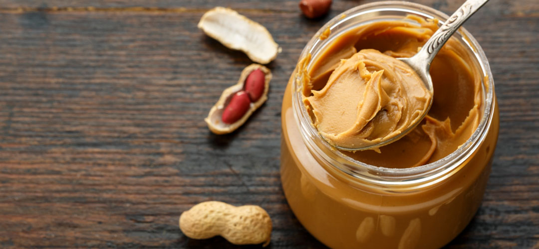 Jar of peanut butter with peanuts on a wooden surface, highlighting molybdenum-rich foods and its role in enzyme function and overall health