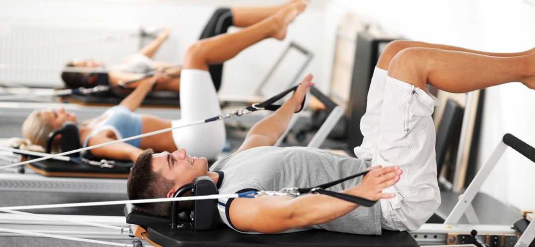 Group of people performing Pilates exercises on reformer machines, showcasing how Pilates can support weight loss and improve overall fitness