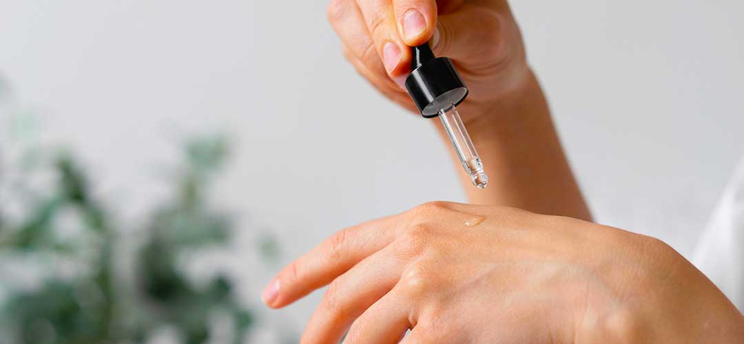 essential oils being added to hands ready for massaging into the skin