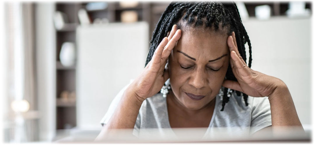 Lady sat at desk rubbing temples due to stress