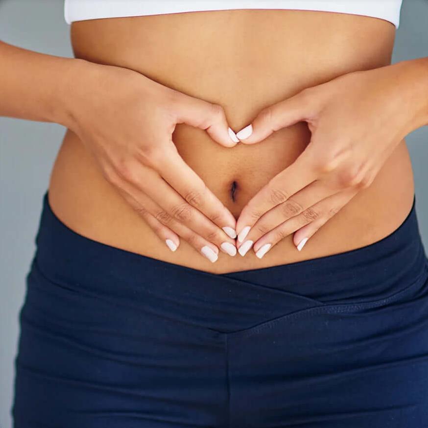 woman holding hands over stomach in a heart shape.