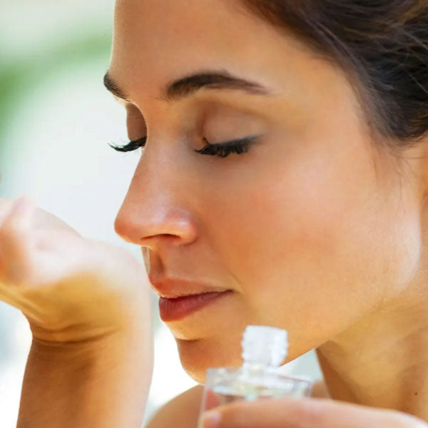 Woman holding a small aromatherapy bottle, with a blurred background.