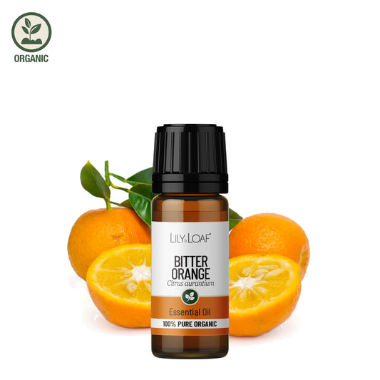 Bottle of Lily & Loaf Bitter Orange essential oil with oranges and leaves on a white background