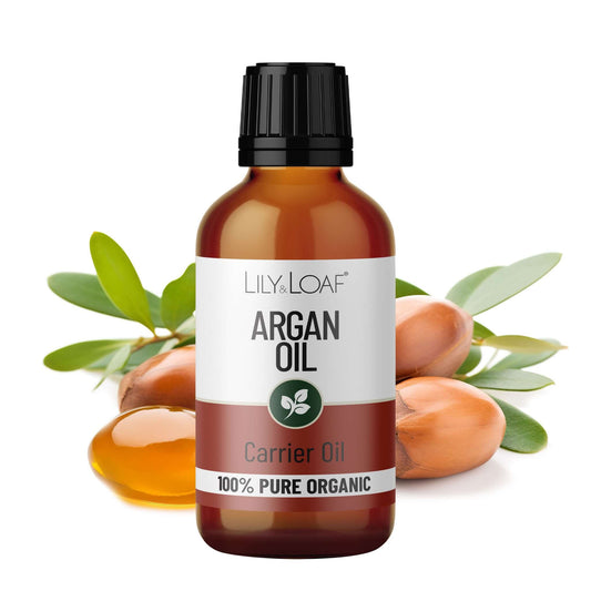 Bottle of Lily & Loaf Argan Oil with argan fruits and leaves on a white background