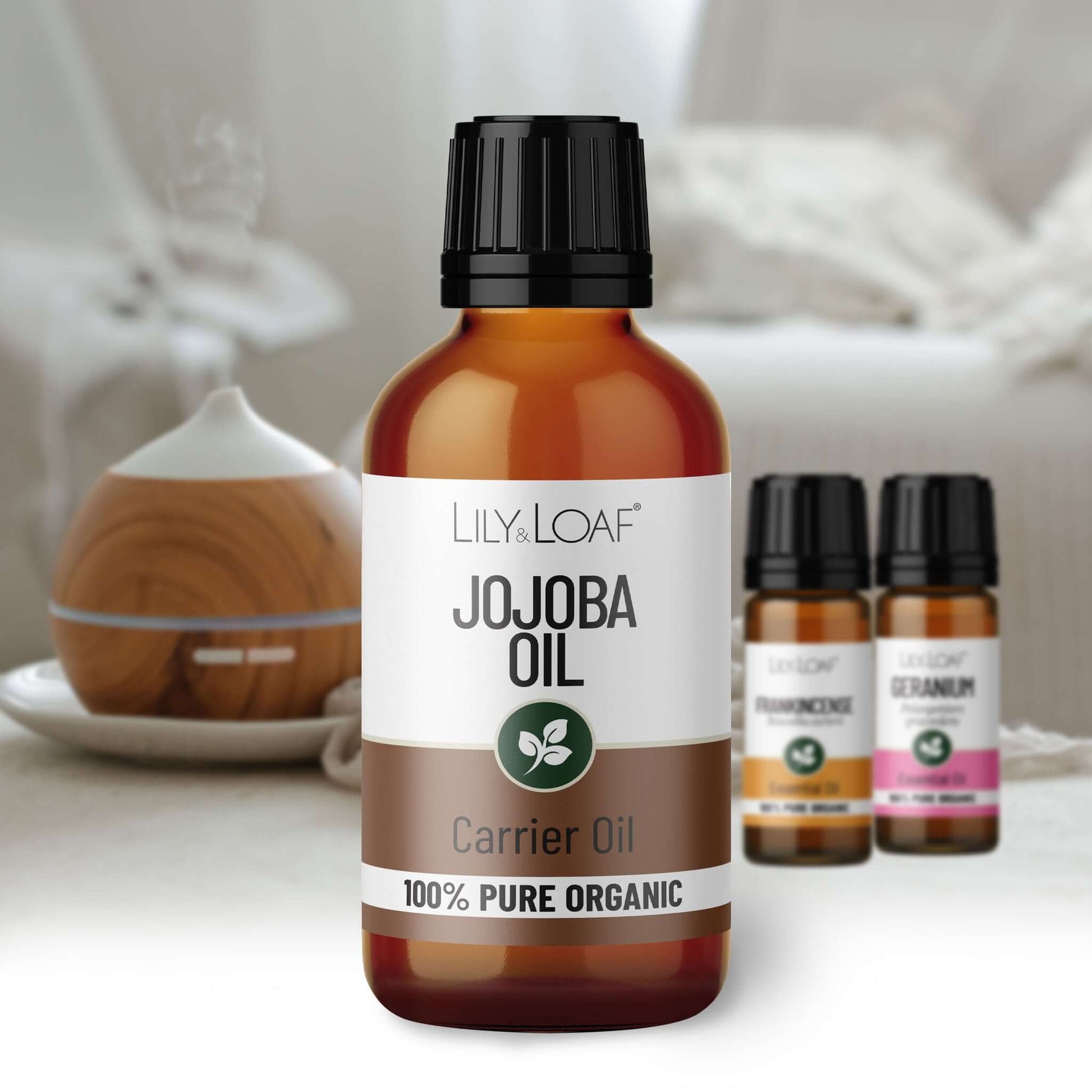 Bottle of Lily & Loaf Jojoba Oil with other essential oil bottles in the background.