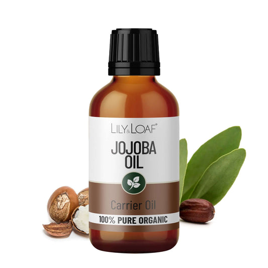 Bottle of Lily &  Loaf Jojoba Oil with jojoba seeds and leaves on a white background