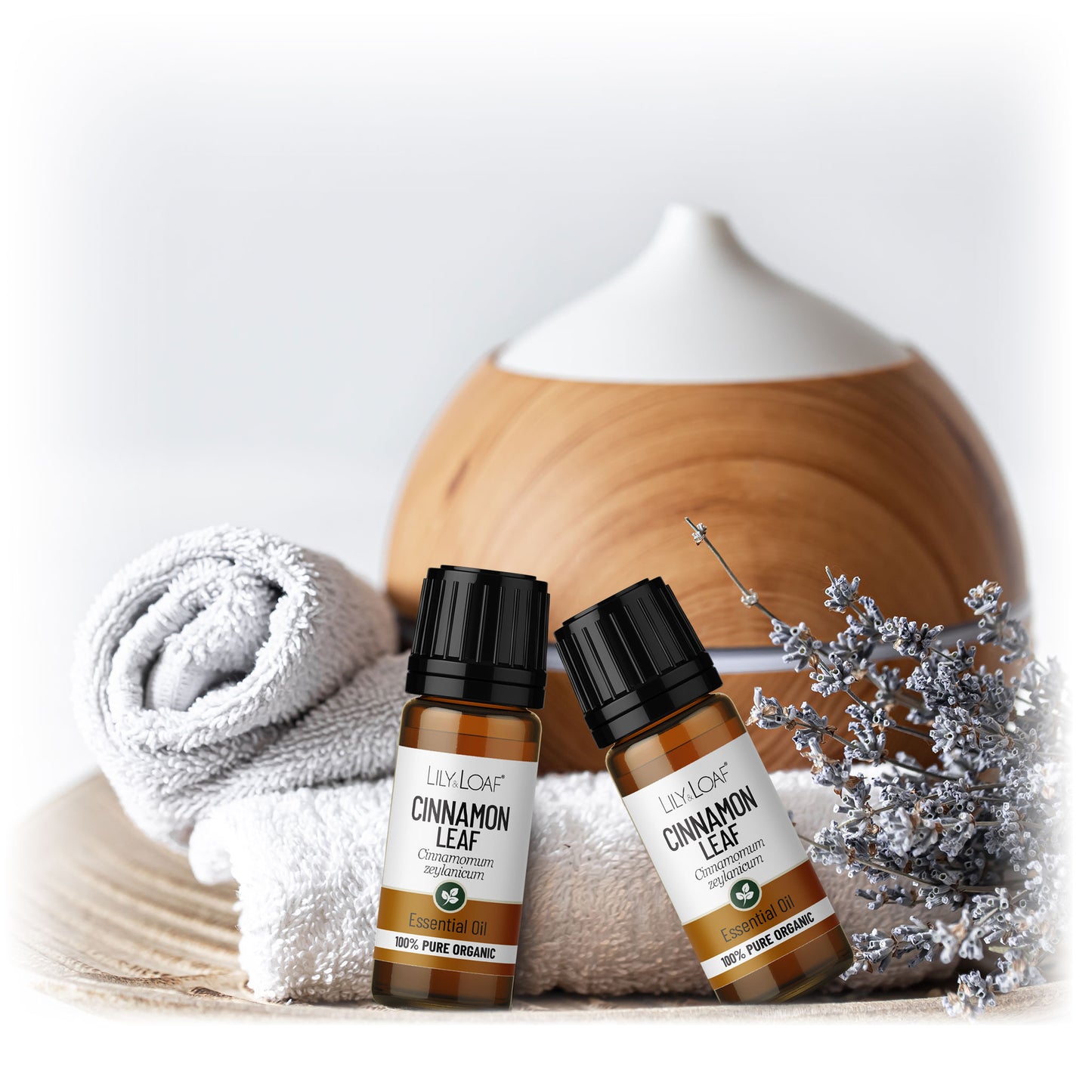 Cinnamon Leaf Organic Essential Oil resting on white towels with a diffuser in the background