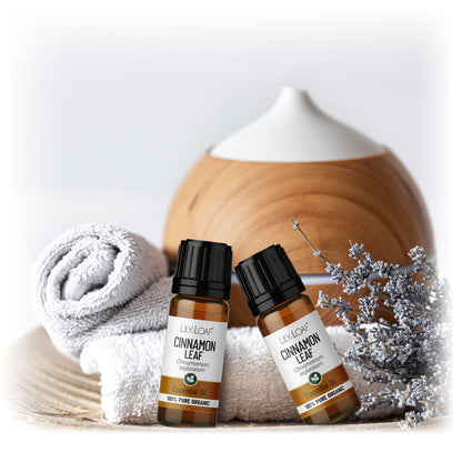 Cinnamon Leaf Organic Essential Oil resting on white towels with a diffuser in the background