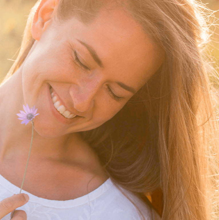 A smiling happy lady holding a purple flower.