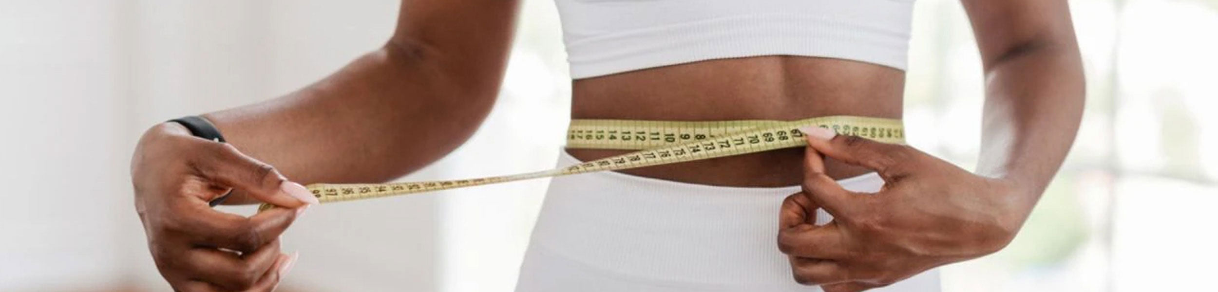 A woman measuring her waist with a tape measure