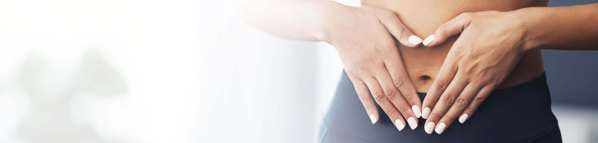 Two hands placed on a person's abdomen against a blurred background