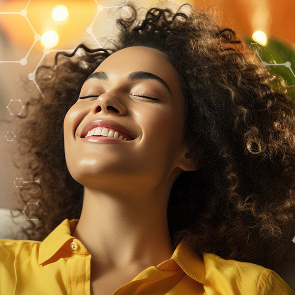 Woman with curly hair wearing a yellow shirt against a warm-toned background