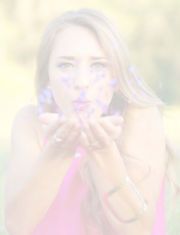 lady blowing purple flower petals towards you