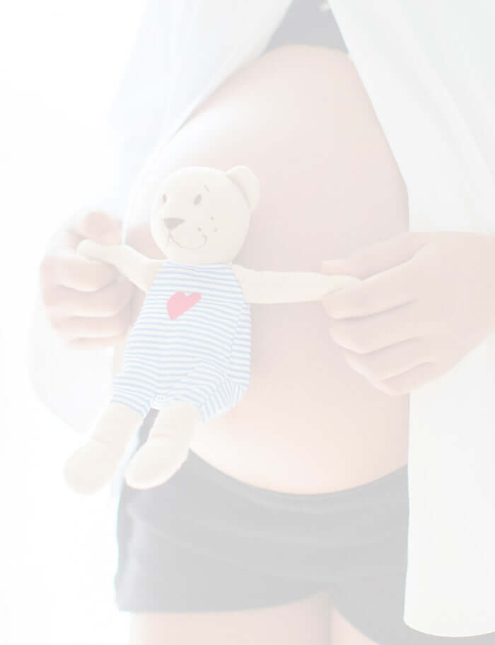 Pregnant lady holding a small cute teddy against her bump