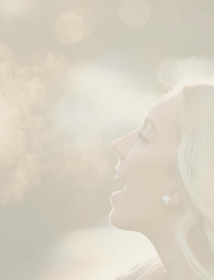 A woman exhaling on a cold day so you can see her breath