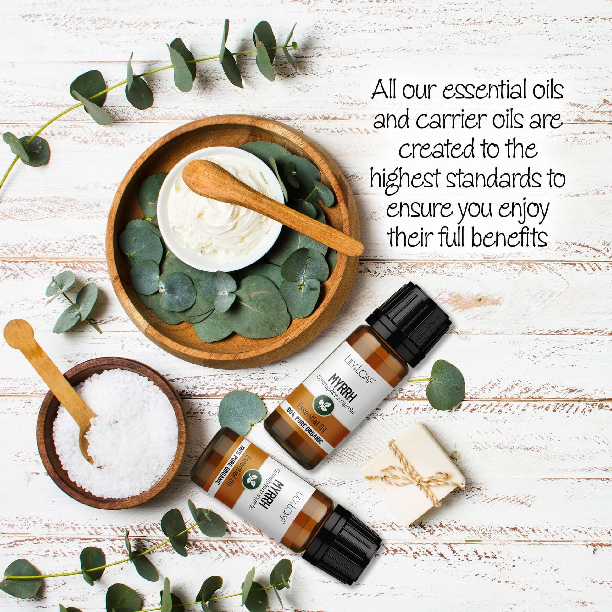 Myrrh Essential oil surrounded by eucalyptus leaves and wooden bowls on a wooden surface