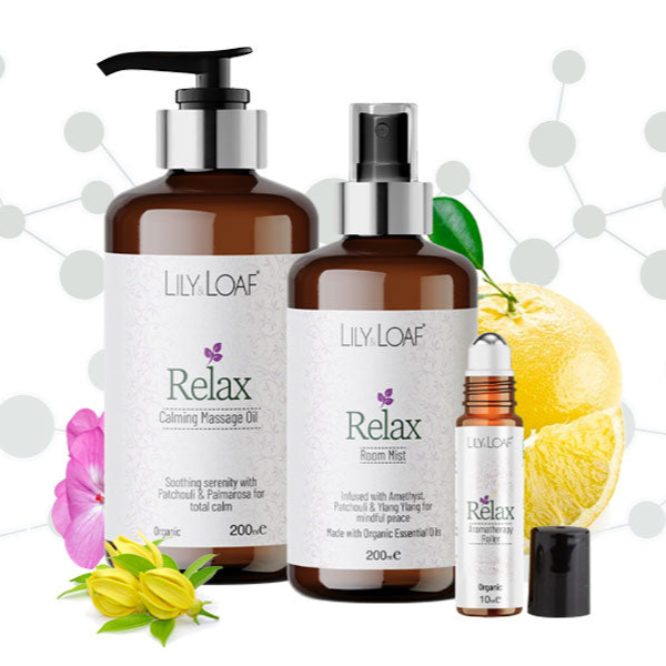 Lily Loaf Relax aromatherapy products with pump, bottle, and roller ball on a white background with flowers and lemons.