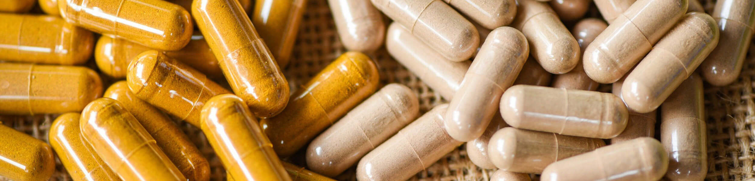 A selection of turmeric and probiotic capsules spilled on hessian 