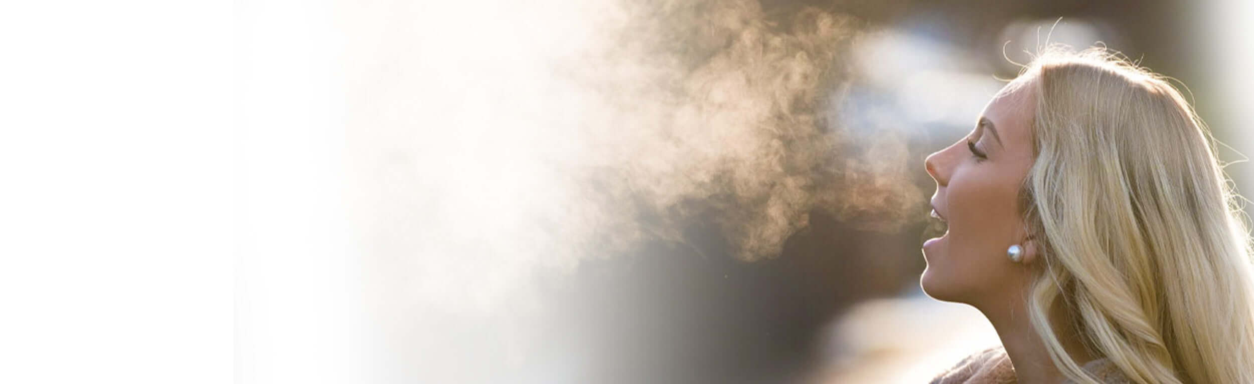 A woman breathing on a cold day so you can see her breath.