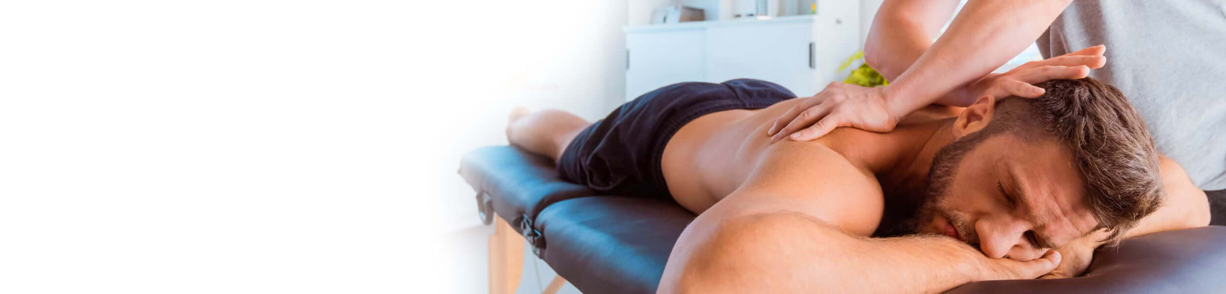 Massage therapist applying pressure to a client's back in a therapy room.