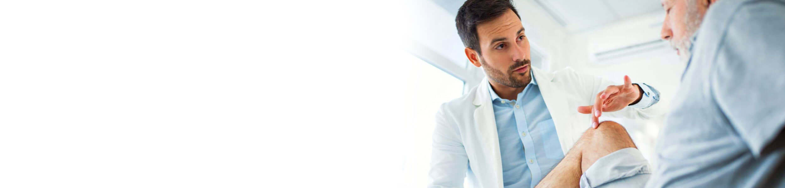 Naturopath examining a patient's knee in a clinical setting.