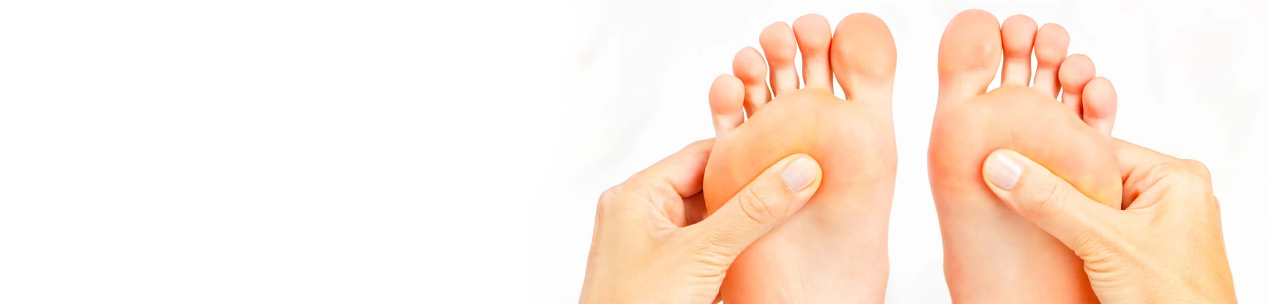 Hands applying pressure to the soles of feet, representing reflexology therapy.