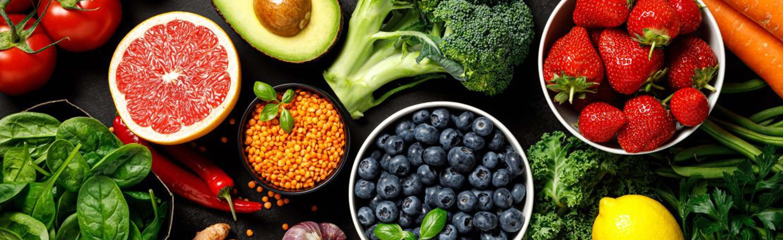 a selection of healthy, nutritional foods including blueberries, strawberries, broccoli and lentils 