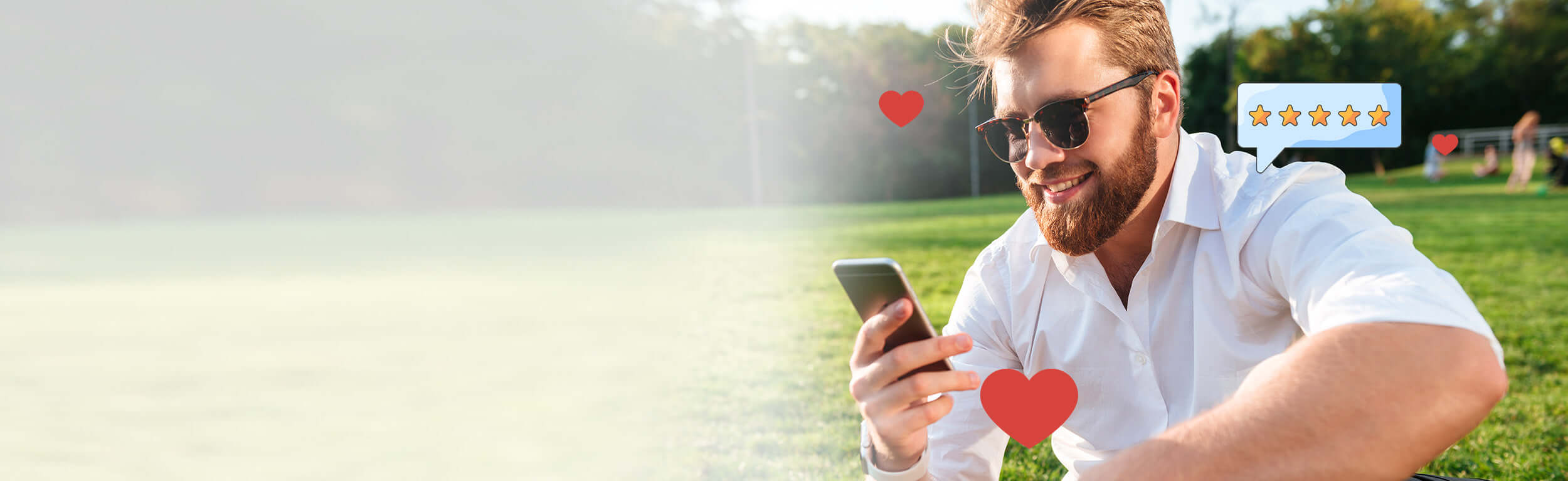 A man sat outside on a field looking at his phone with cartoon stars and love hearts superimposed