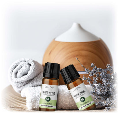 Two bottles of Lily & Loaf White Thyme essential oil with a diffuser and towel in the background.