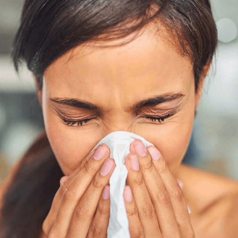 A woman sneezing into a tissue representing allergies