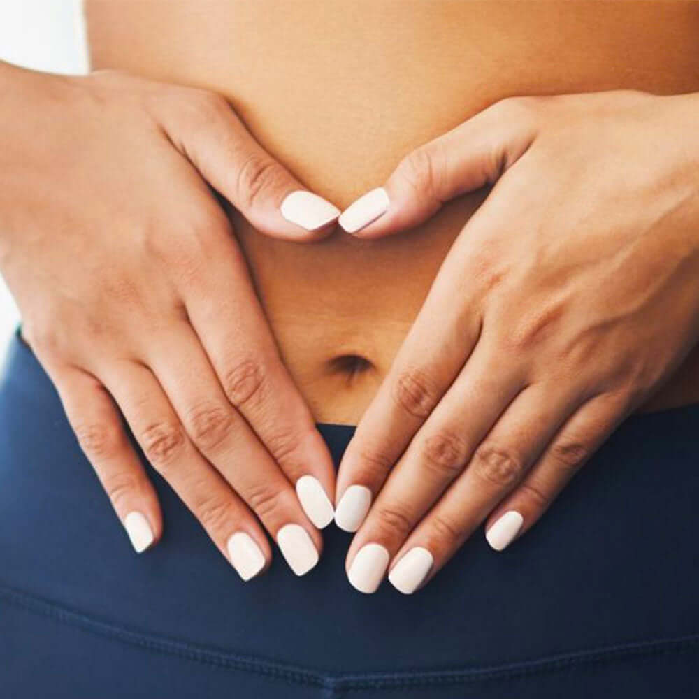 Close-up of hands making a heart shape over a belly