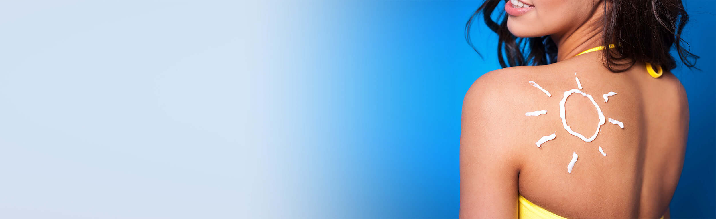 lady looking over shoulder with sunscreen on her skin in the shape of a sun